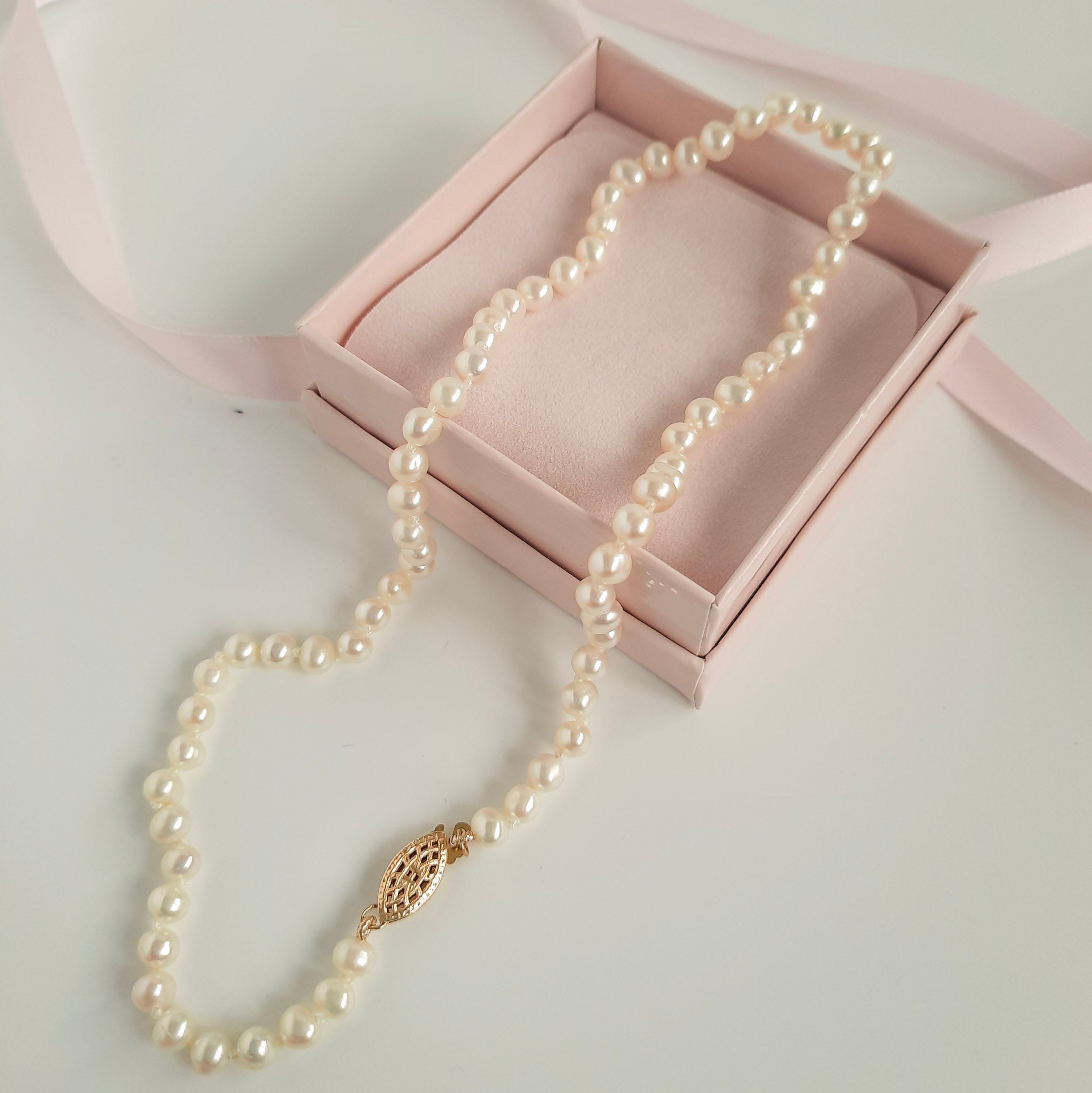 pearl necklace on a pink box and white background