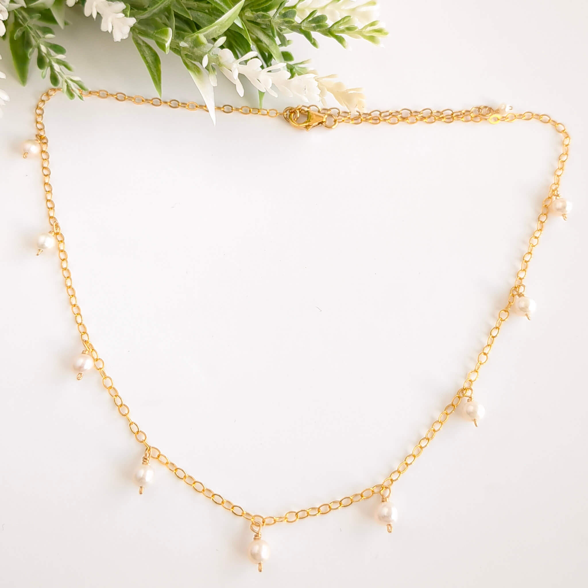 Gold chain necklace with intermittent pearls dropping around the chain