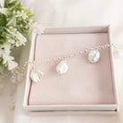 Pearl bracelet on a pink jewelry box with flowers in the background