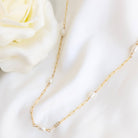 Gold chain necklace with pearls on a white fabric background