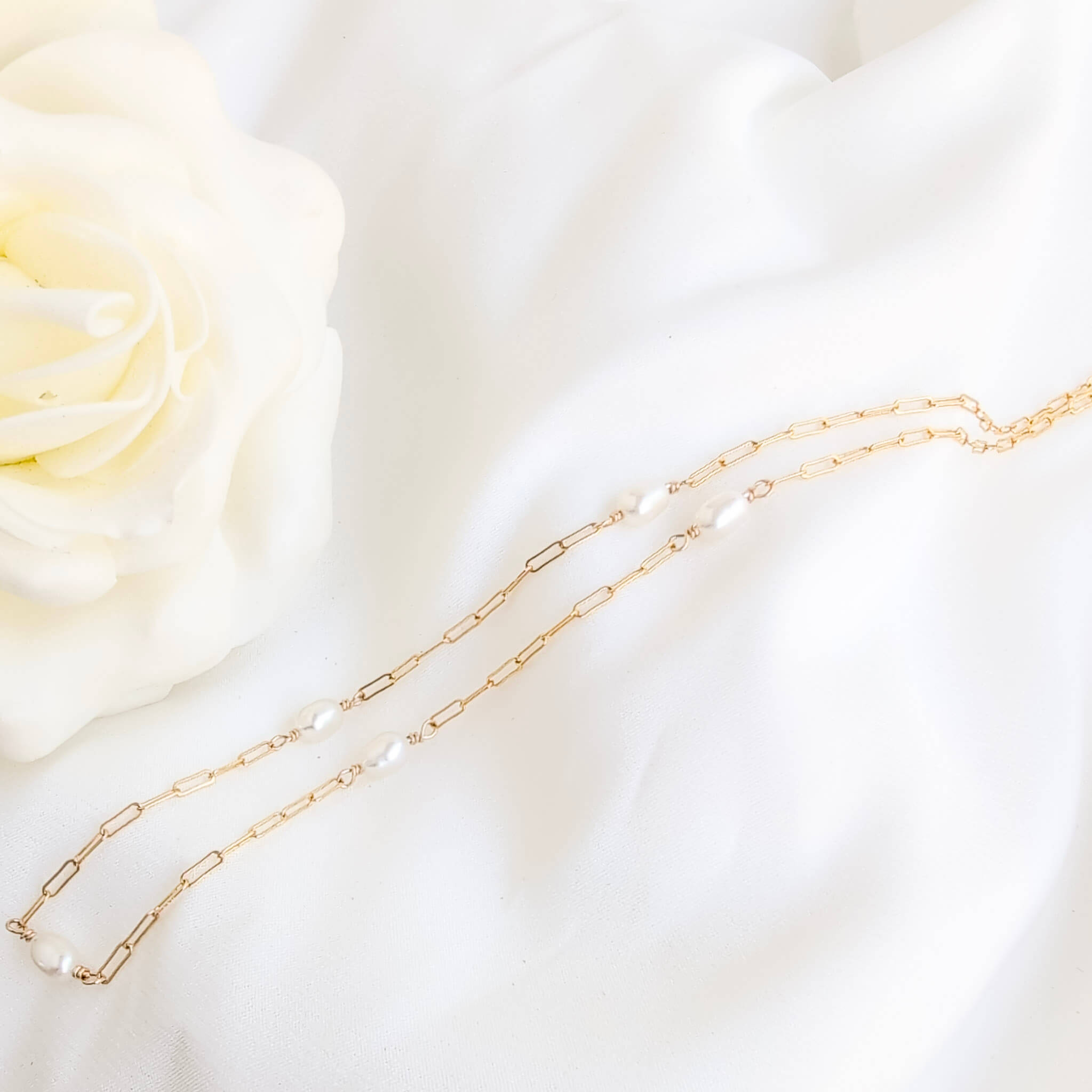 Gold chain necklace on a soft white fabric background