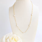 Gold chain necklace on a mannequin with a white rose in the foreground