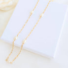 Gold chain necklace with pearls on a white background