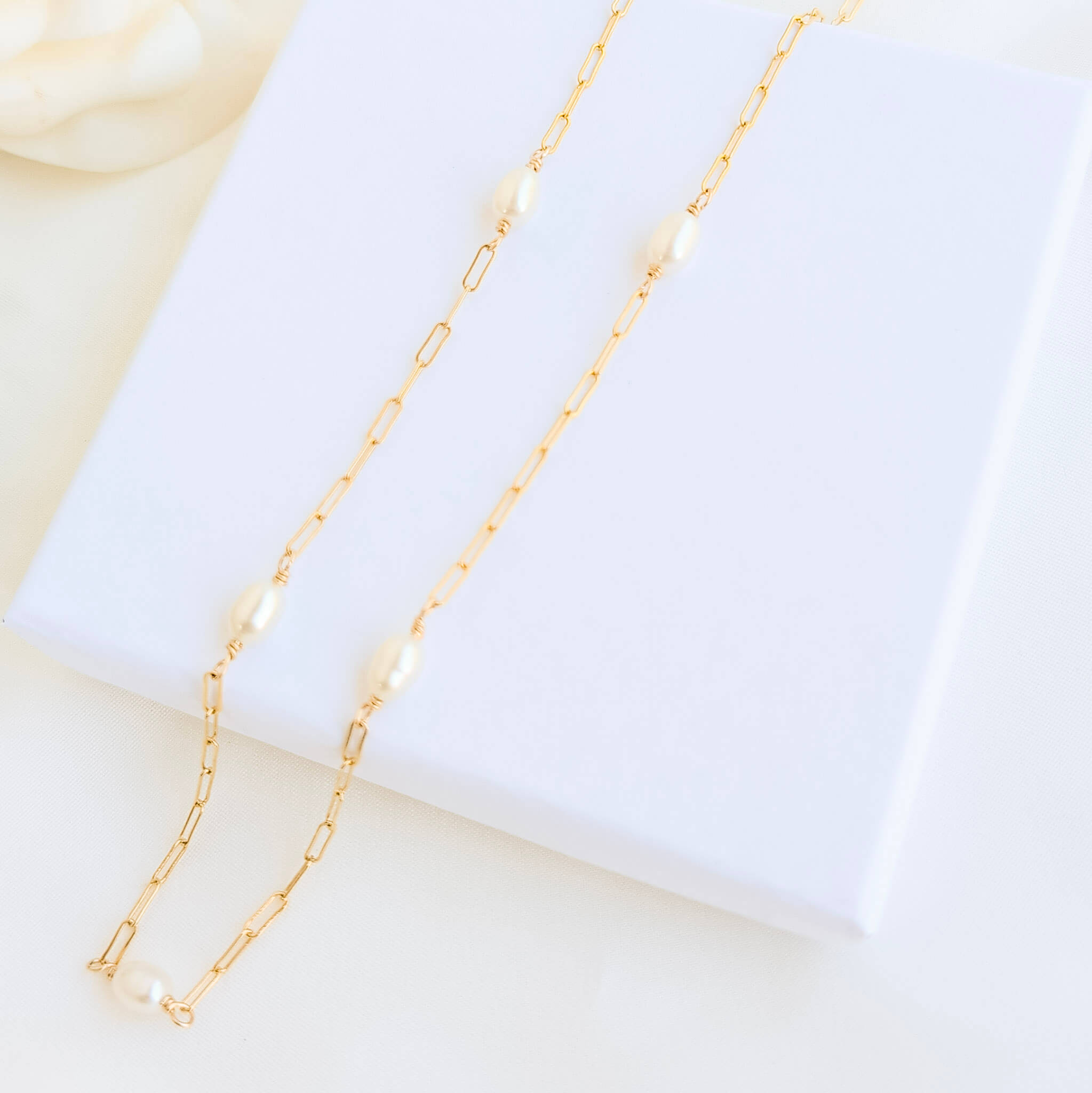 Gold chain necklace with pearls on a white background