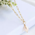 Gold chain necklace with a pearl pendant on a light background