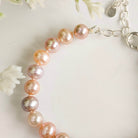 Pearl bracelet with pink and silver chain on a light background