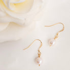 Pearl earrings with gold hooks on a soft white background