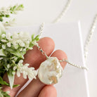 Pearl necklace held by a hand with a white background